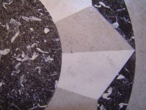 Sur un petit guéridon, imitation de marqueterie de faux marbres noirs, gris, blanc, de style Néoclassique,